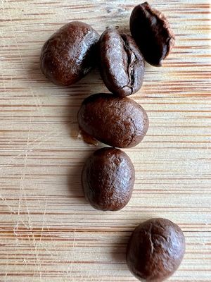 Roasted coffee beans on a wood surface.